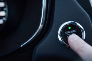 Finger pressing a vehicle engine start button inside a car
